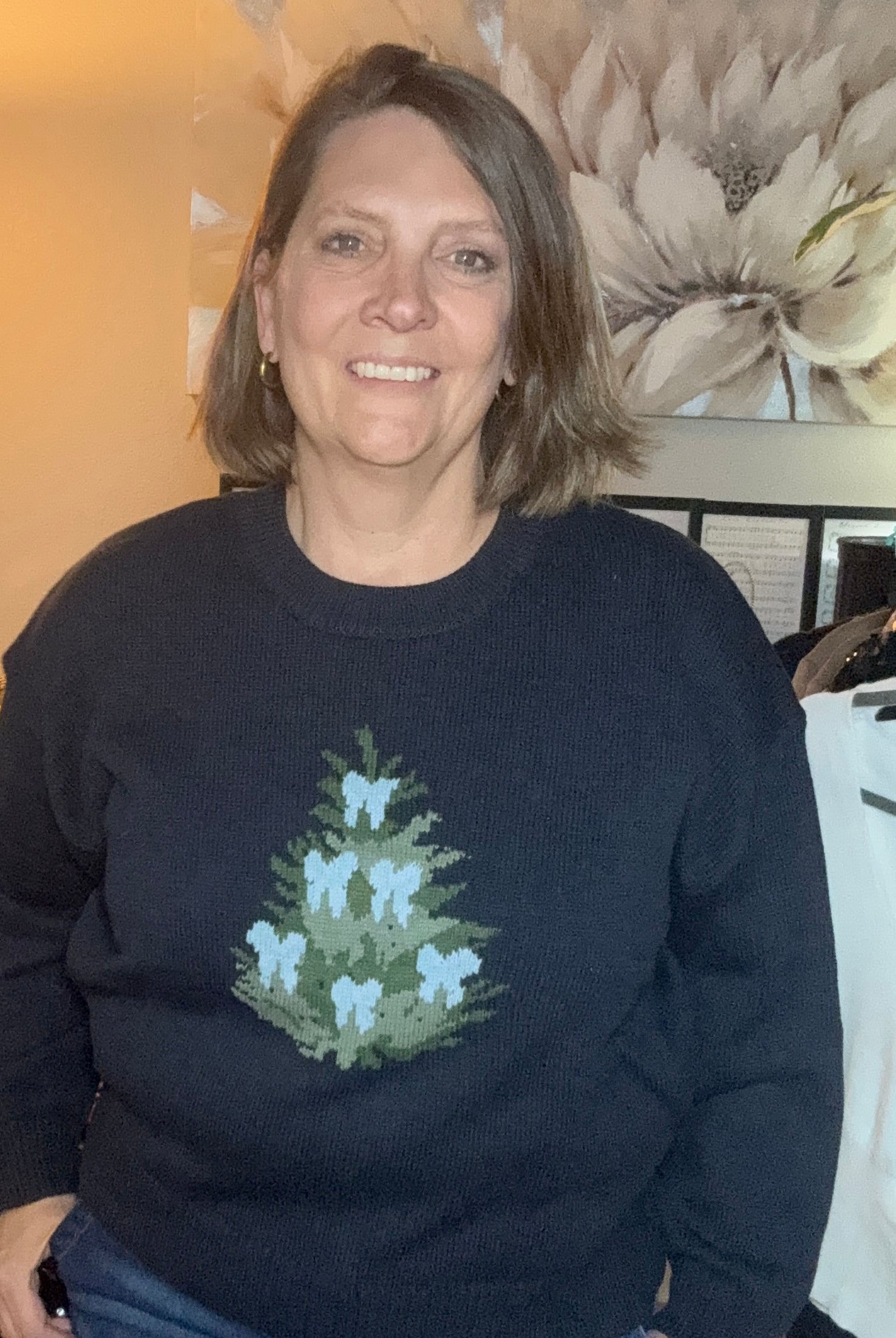 Woman wearing a black sweater with a floral design in an indoor setting