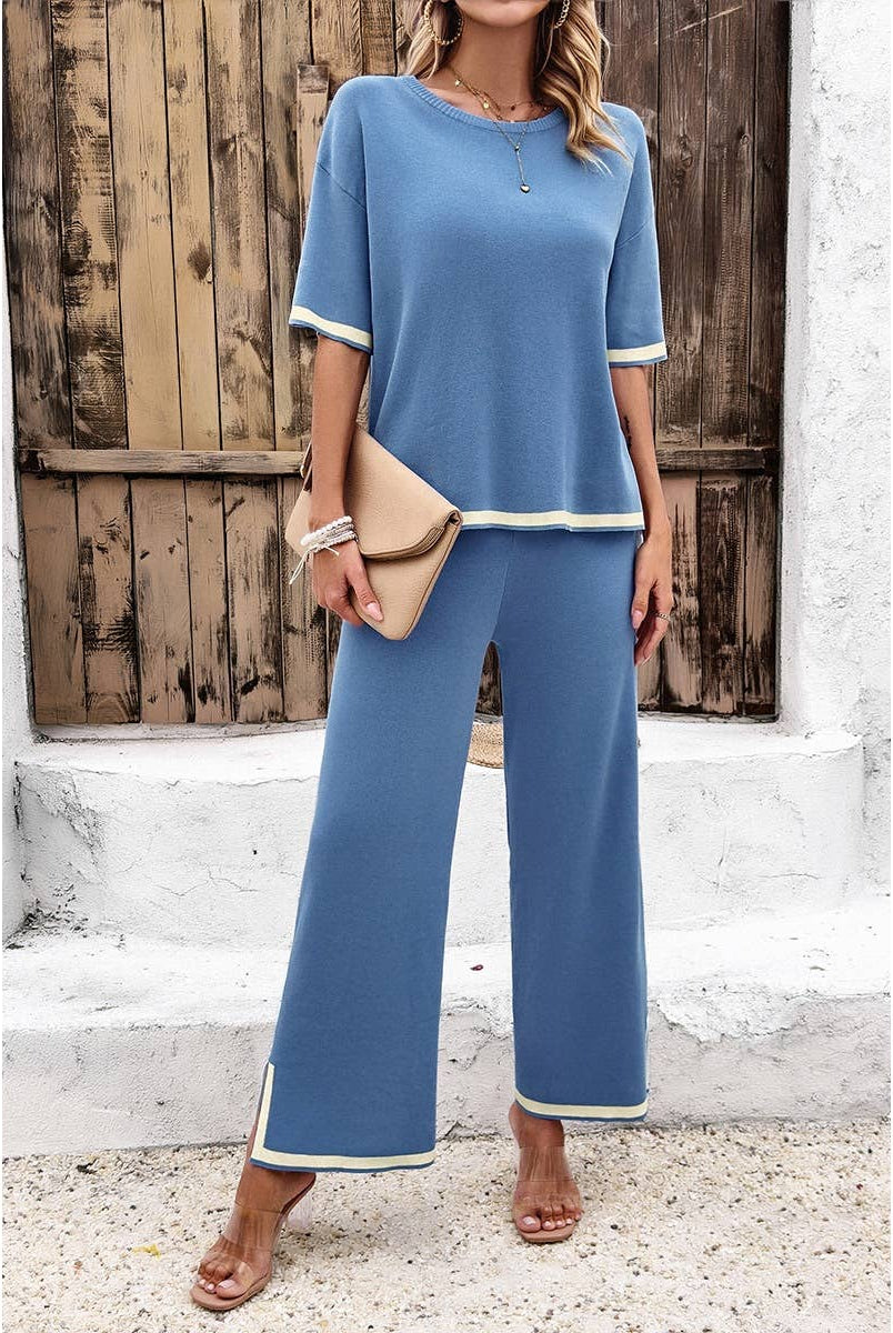 Woman wearing a blue outfit with white trim standing in front of a wooden door.
