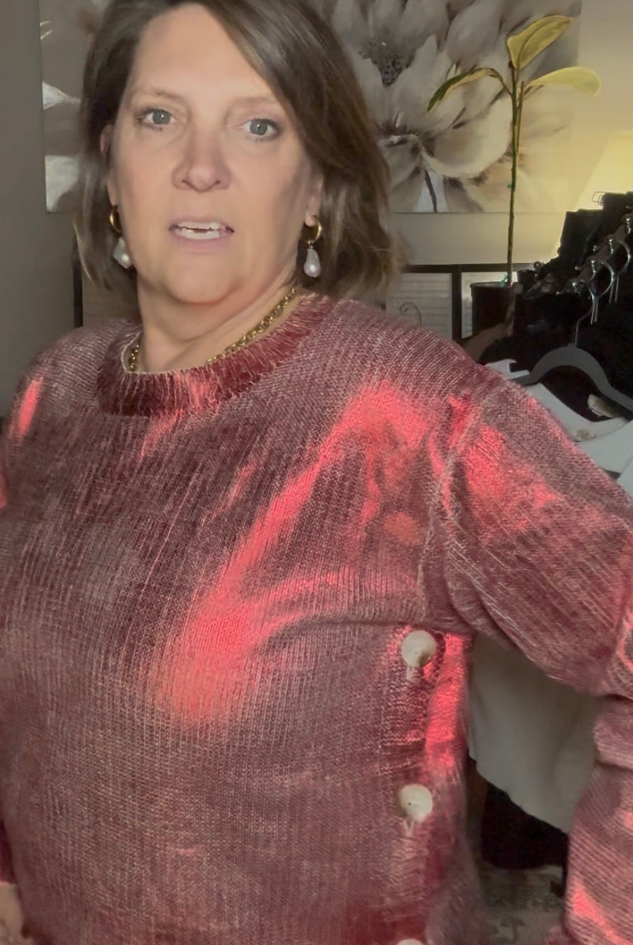 Woman wearing a red and brown patterned sweater in an indoor setting with blurred background