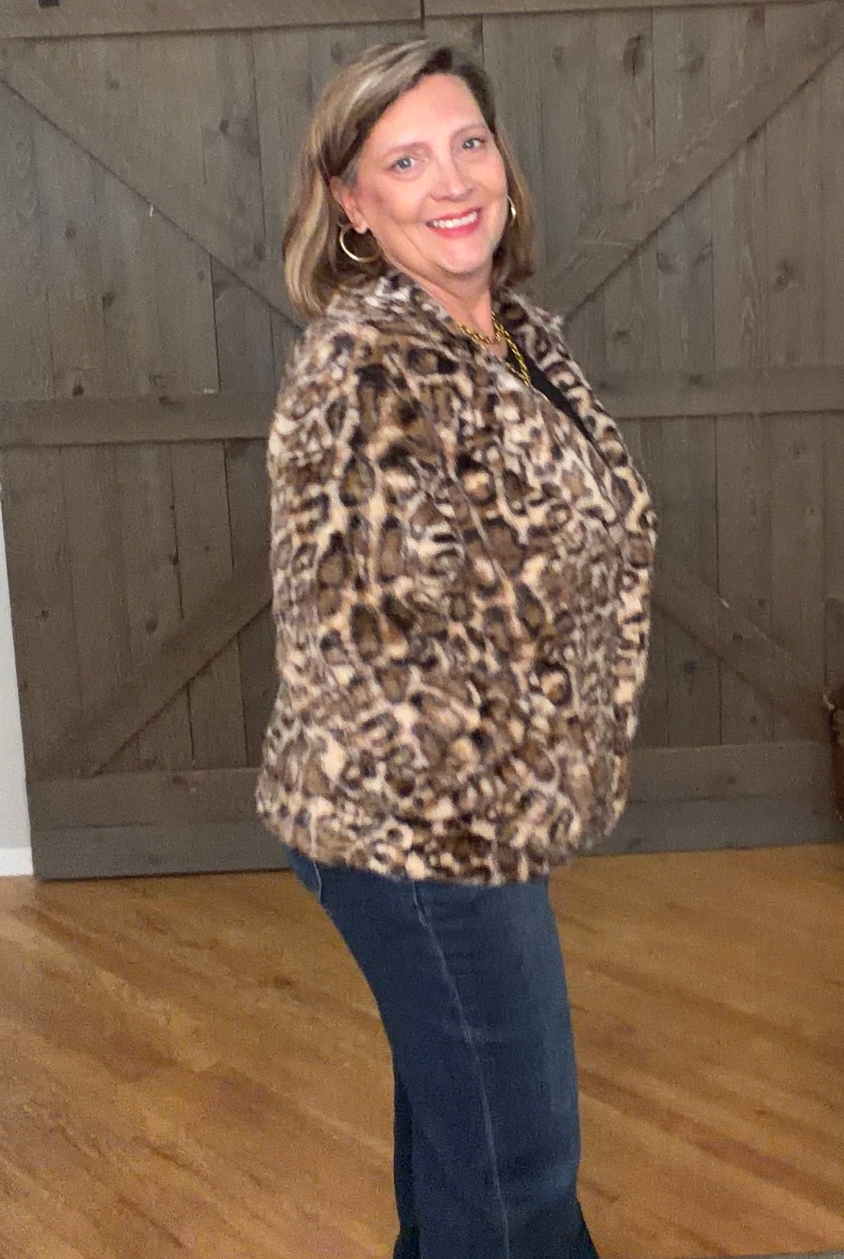 Woman in Wildly Chic Leopard Jacket and jeans against a barnwood door