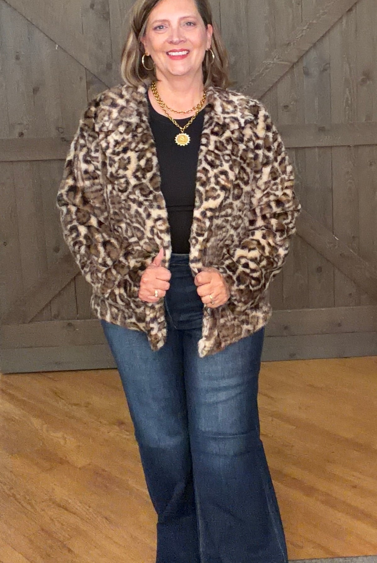 Woman in Wildly Chic Leopard Jacket and jeans against a barnwood door