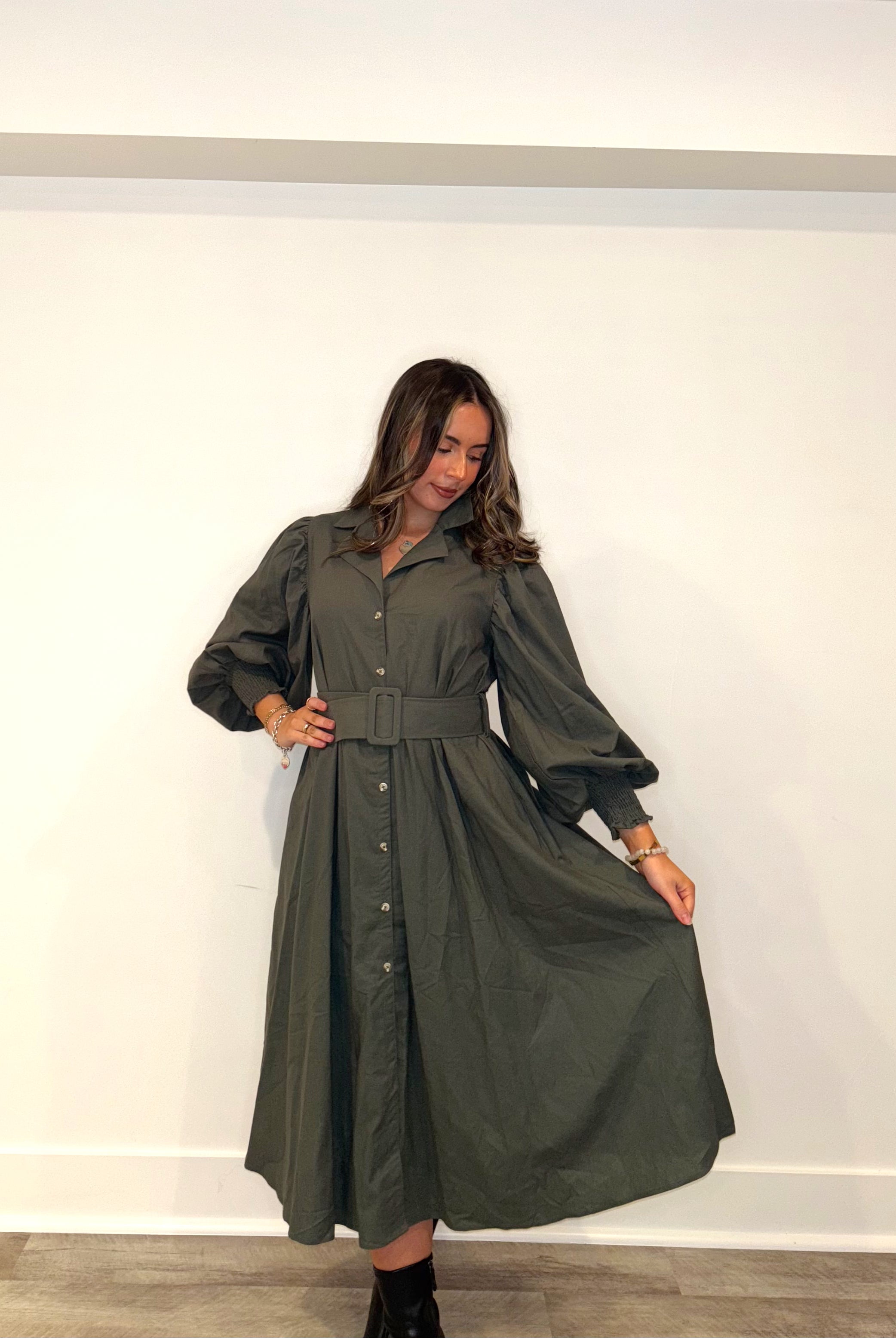 Woman wearing a green dress against a white wall