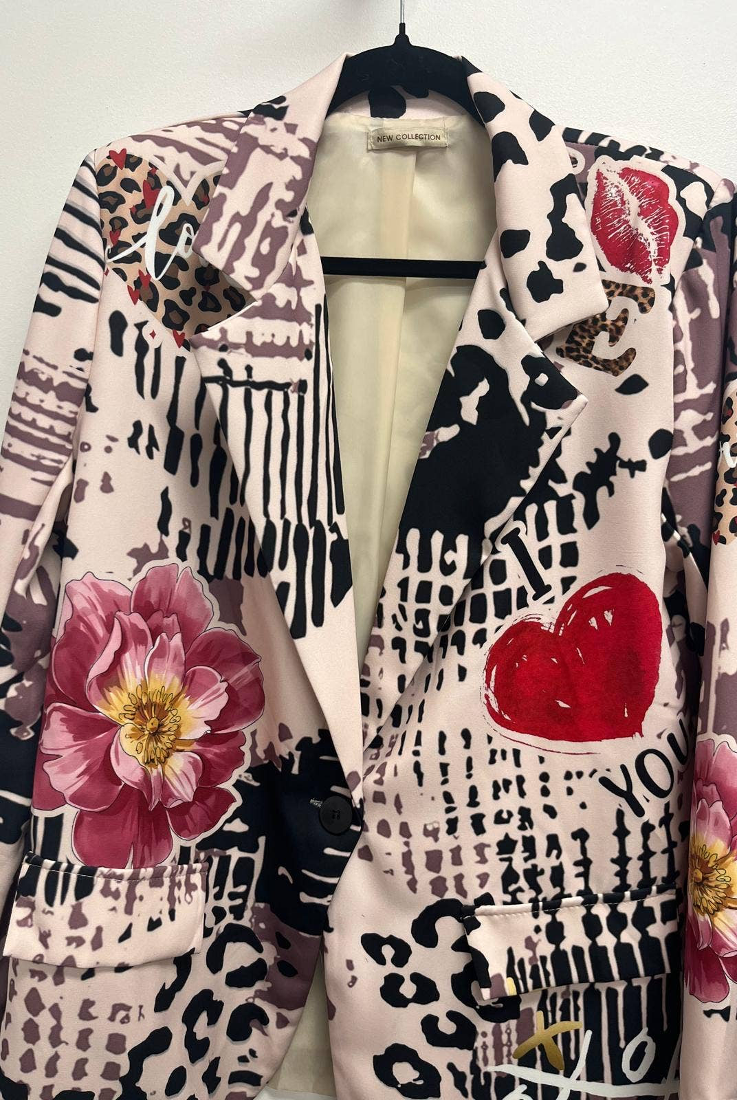 Patterned jacket with floral and heart designs on a mannequin against a white background