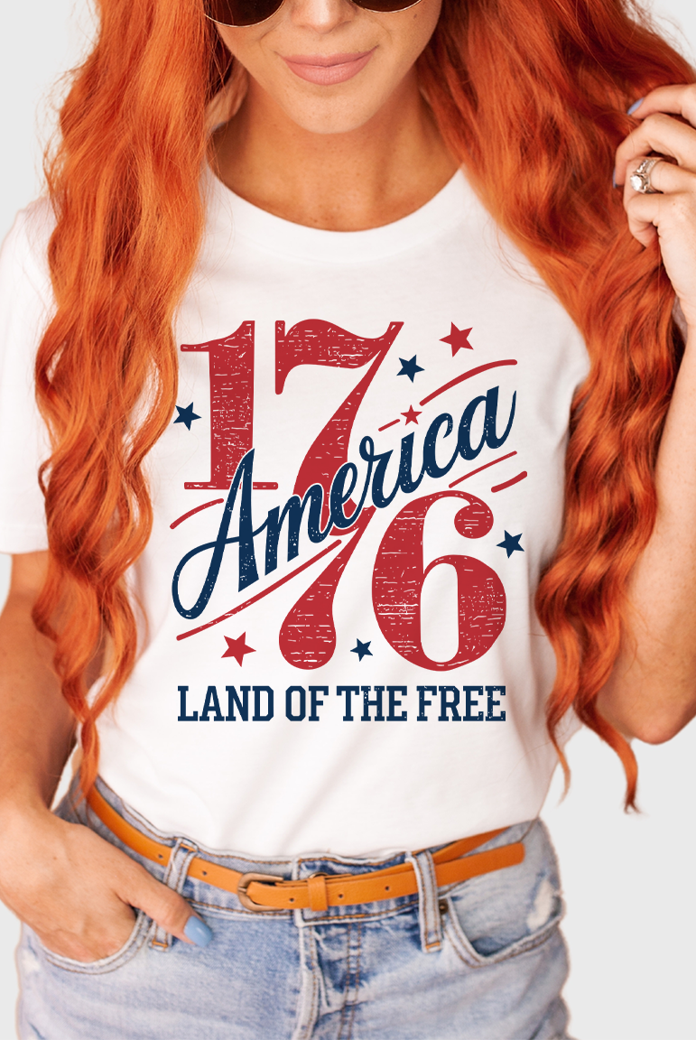 Person wearing a white t-shirt with 'America 1776 Land of the Free' design.
