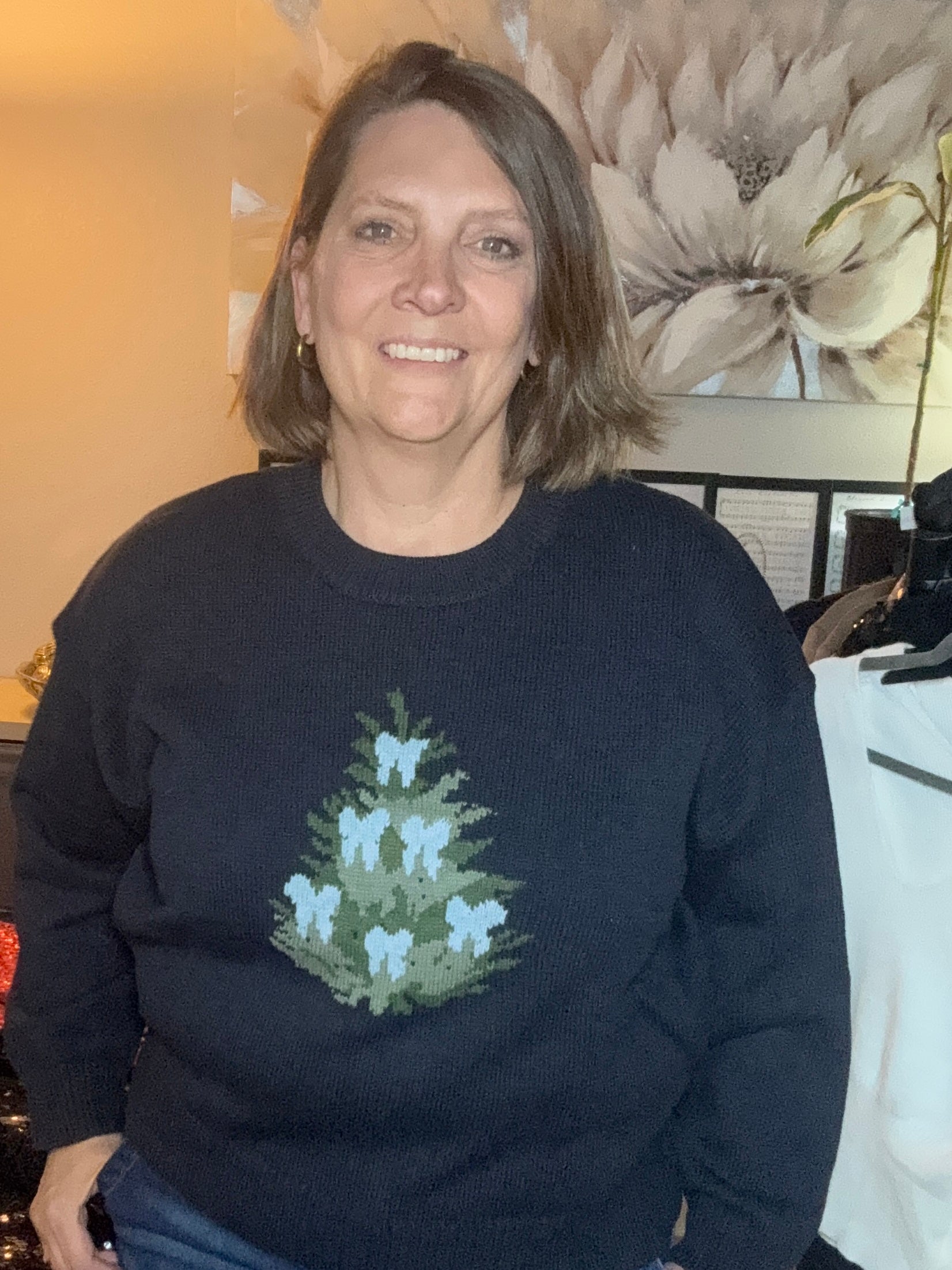 Woman wearing a black sweater with a floral design in an indoor setting