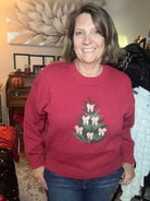 Person wearing a red sweater with a Christmas tree decorated with pink bows. 