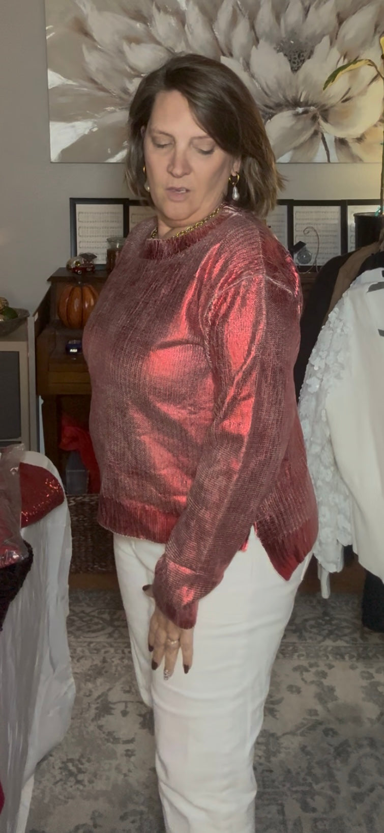 Woman wearing a red metallic jacket and white pants in an indoor setting.