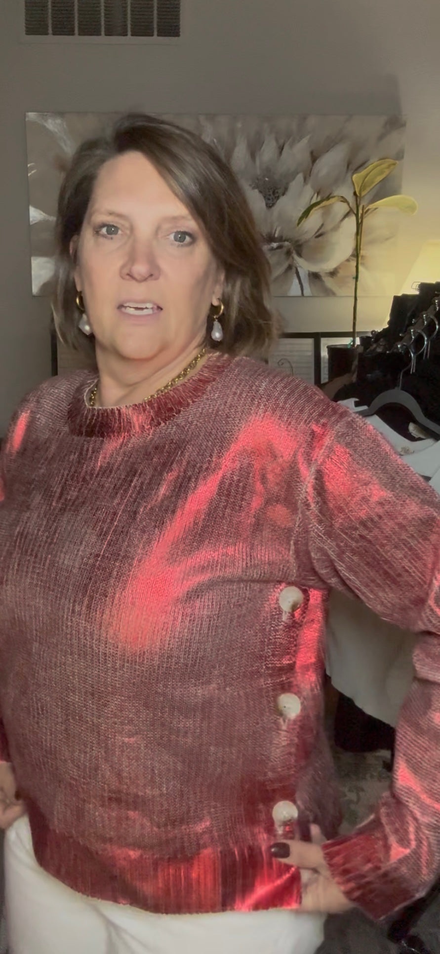 Woman wearing a red and brown patterned sweater in an indoor setting with blurred background