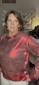 Woman wearing a red and brown patterned sweater in an indoor setting with blurred background