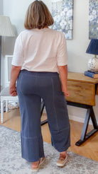 Person wearing a white shirt and blue pants in a room with a desk and lamp.