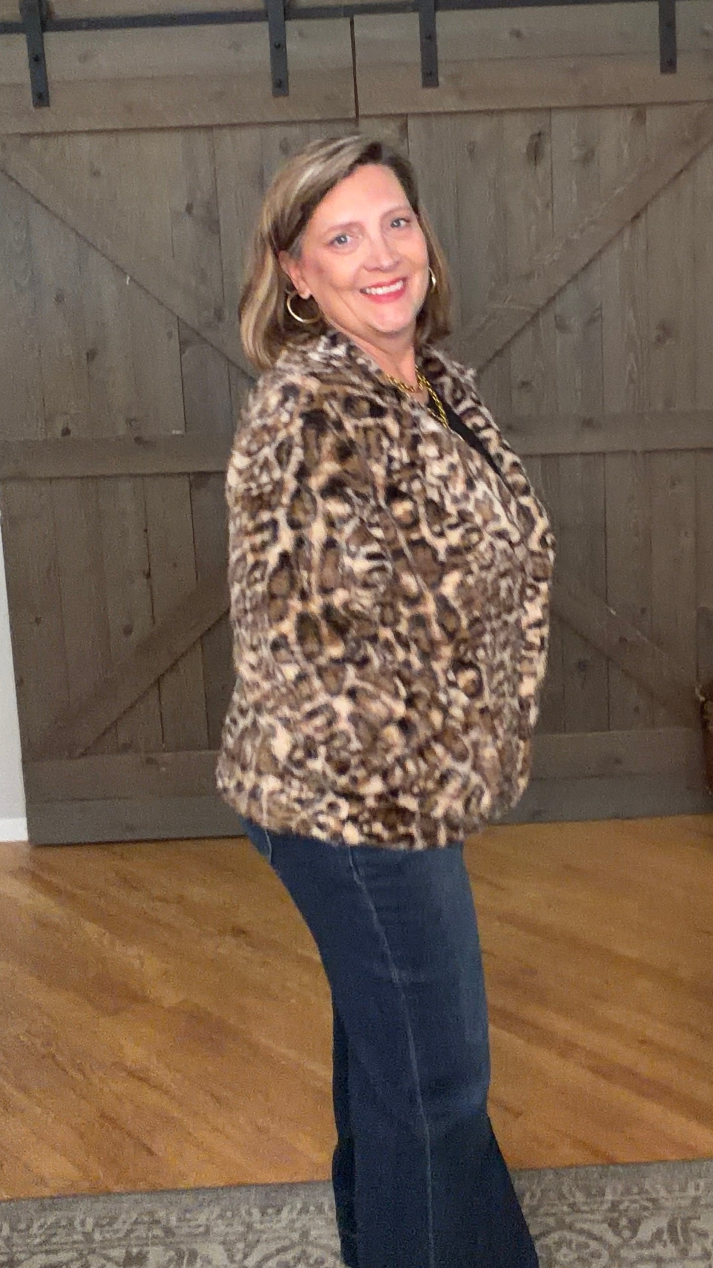 Woman in Wildly Chic Leopard Jacket and jeans against a barnwood door