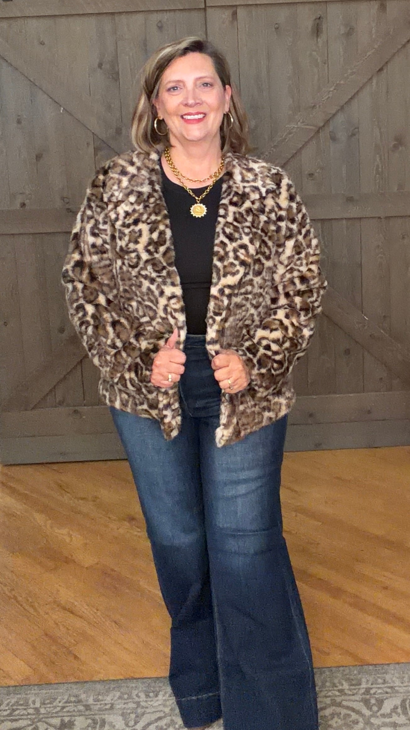 Woman in Wildly Chic Leopard Jacket and jeans against a barnwood door