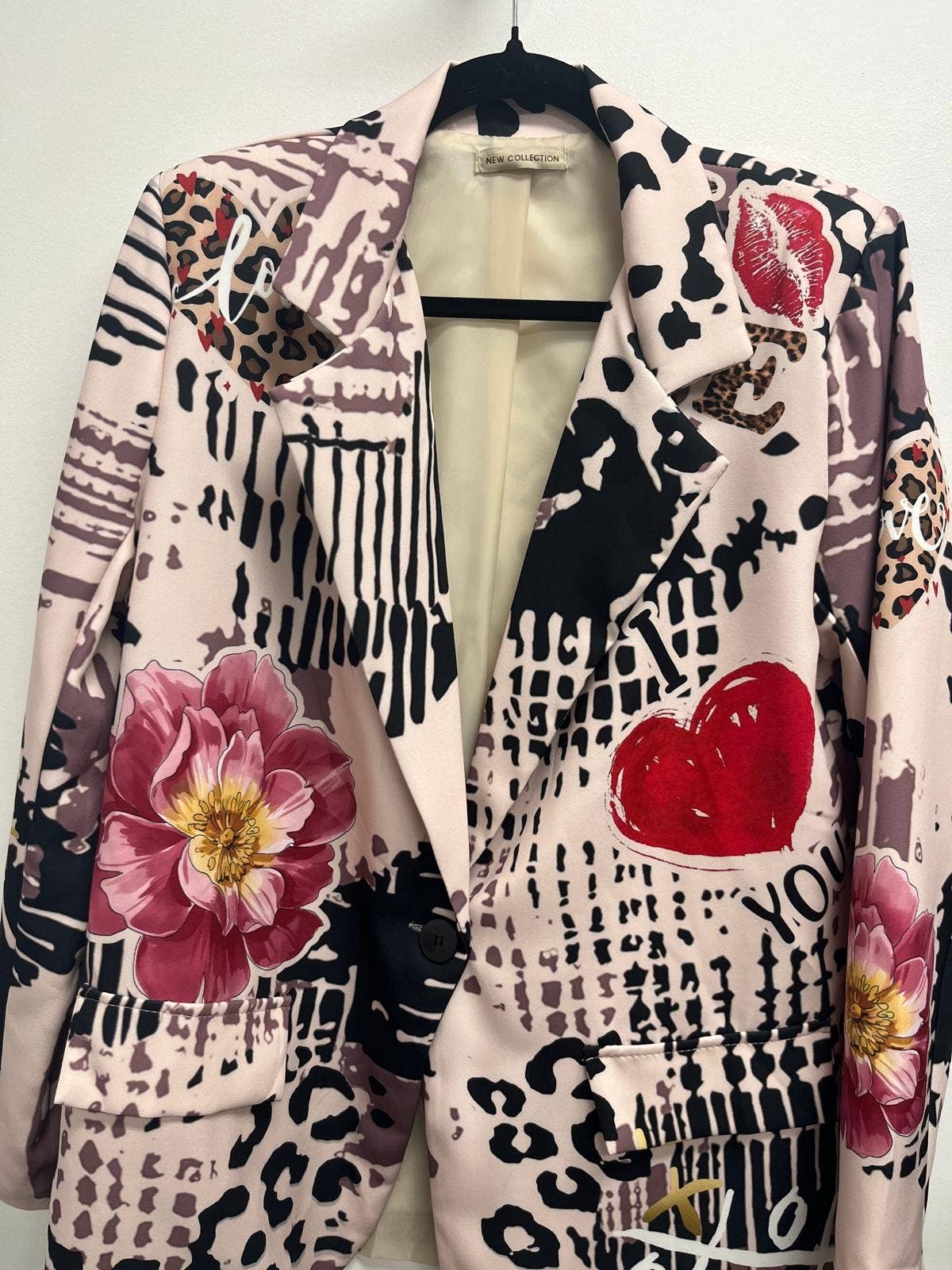 Patterned jacket with floral and heart designs on a mannequin against a white background